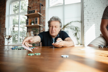 Exciting. Happy mature man playing cards and drinking wine with friends. Looks delighted, excited. Caucasian man gambling at home. Sincere emotions, wellbeing, facial expression concept. Good old age.