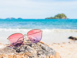Pink sunglasses on the beach.