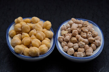 dry and soaked chickpeas in a bowl on a dark background