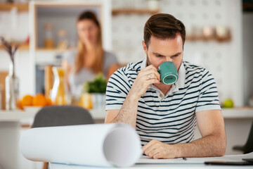 Young man working and drinking coffee. Handsome man working at home.	