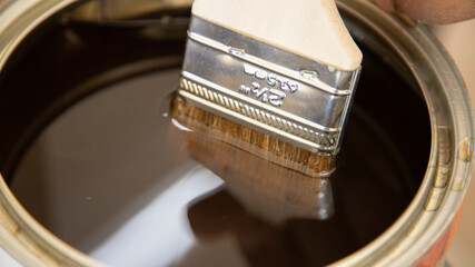 Paint brush submerged in a can of varnish