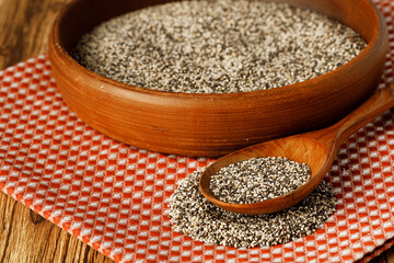 Chia seeds in a bowl with wooden spoon