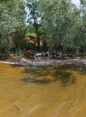 Quickly folding tent, chairs, table, camping and vacation, equipment for tourism and sports. A couple of people, man and woman, family, enjoy the moment. A motorcycle and a hammock. Vertical photo