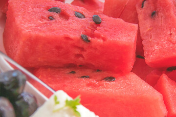 Watermelon cut in pieces with white cheese and black olives for light healthy Mediterranean breakfast