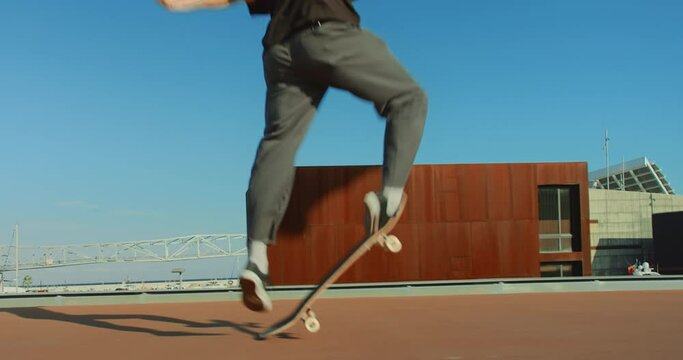 Slow motion cool young man rides in and out of frame on skateboard. Millennial generation z teenager does kick flip while skateboarding. Urban city spot 