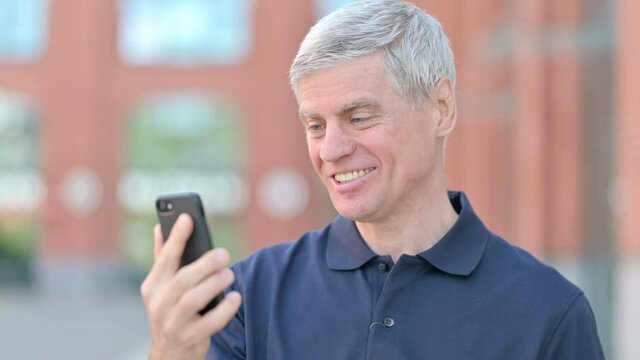Outdoor Portrait of Middle Aged Man Celebrating Success on Smartphone