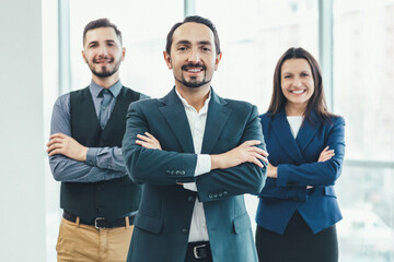 Group portrait of a professional business team looking confidently at camera with their hands folded.
