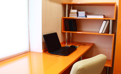The interior of the home desktop. Orange table and bookshelves.