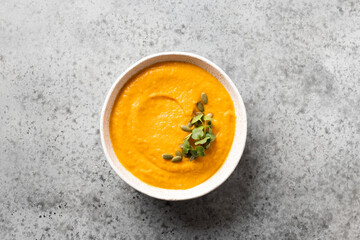 Pumpkin soup garnish microgreens on grey stone table. View from above. Minimal style.