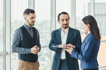 Portrait of two employees and their boss signing new project.