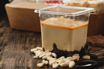 Creamy dessert in a plastic box on wooden table