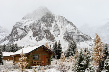 wooden house in the mountains in winter with a peak behind