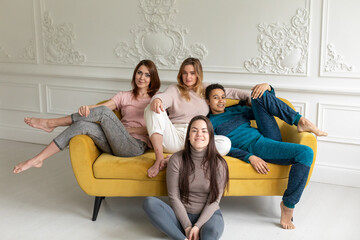 Four girls friends sit at home on a chair and talk. girls spend time together at home