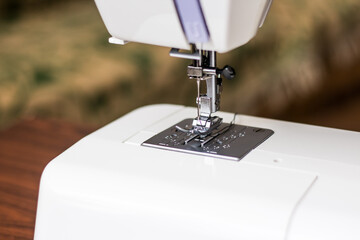 Close up view of sewing process. Professional manufacturing machine at workplace. Needle of the sewing machine. Light blurred background.