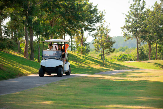 Two asian man golfer driving golfcar on road in golf course