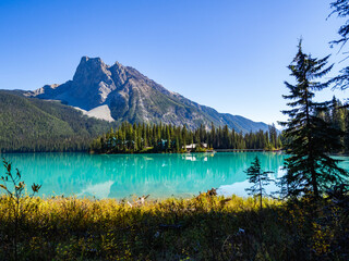 bright turquoise lake in front of a very tall mountain in summer with a clear sky