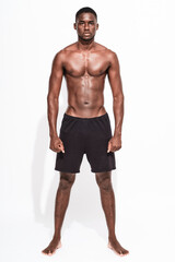 Fototapeta na wymiar Bare chested black fitness man looking at camera wearing sport short trousers