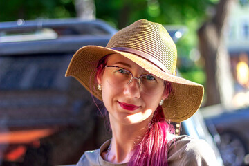 A young hipster woman looks into the camera, beautiful face, expressive eyes, posing in an urban area on an autumn day, outdoors, stylish hat and transparent glasses. The concept of happy people