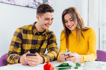 Couple in love having fun posting, commenting or choosing photos to upload into their profile in...