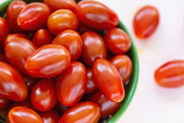 Fresh red cherry tomatoes in a bowl on light background. Selective focus, close up, copy space