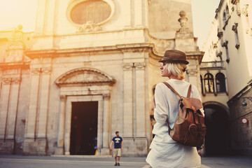 Back view of a young female wanderer out sightseeing in a foreign city during weekend overseas,...