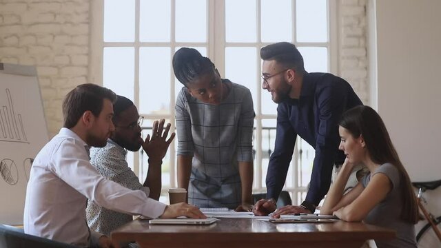 Happy friendly diverse male colleagues give high five at multiracial group meeting celebrate find solution good teamwork result, thanking for help in common work express partnership agreement concept