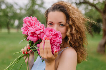 Naklejka premium girl model mother holding peonies and flowers in her dress gently presses them to herself on the nature in the park