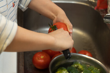 The cook is removing the top of the tomato with a knife.