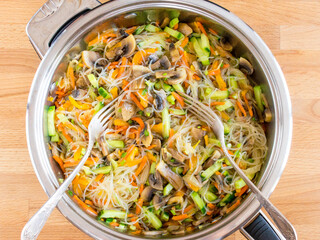 Fjunchoza with mushrooms and vegetables. Mixed ingredients in a pan, top view