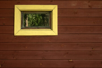 Yellow rectangular window in a wooden wall