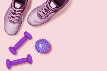 Train at home. Sneakers, dumbbels and massage ball on pink background. Flat lay picture.