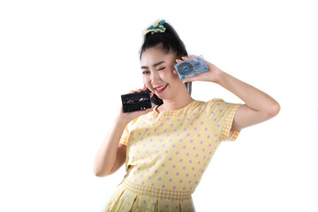 Young Asia woman in retro fashion yellow dress holding a cassette tape on a white background