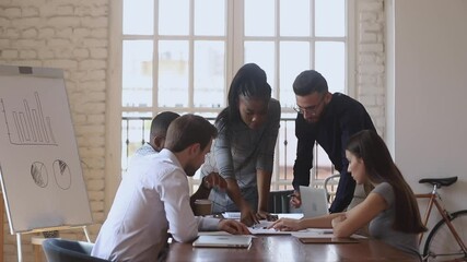 Corporate teamwork brainstorm concept, focused multiracial team talk share ideas working together on new business plan at office briefing, diverse workers group discussing paperwork at meeting table