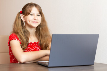 Little girl doing homework on laptop at home. Distance learning.