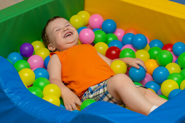 Fototapeta na wymiar Little boy is laughing in the bubble pool