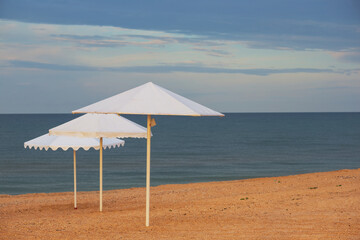 white sun umbrella on a sandy sea beach, summer sea vacation background