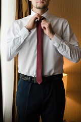 man straightens his tie, groom tightens his tie, man in white shirt, wedding day, business style