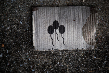 A piece of old cardboard on the ground with balloon signs stamped in black and white