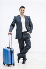 Full-length shot of the businessman holding a suitcase, hand in pocket, over white background.