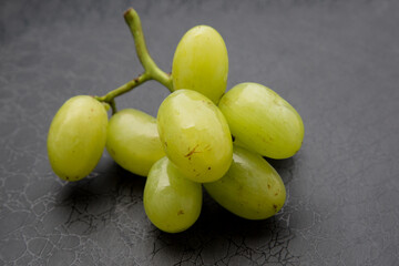 a small sprig of green grapes on a dark background