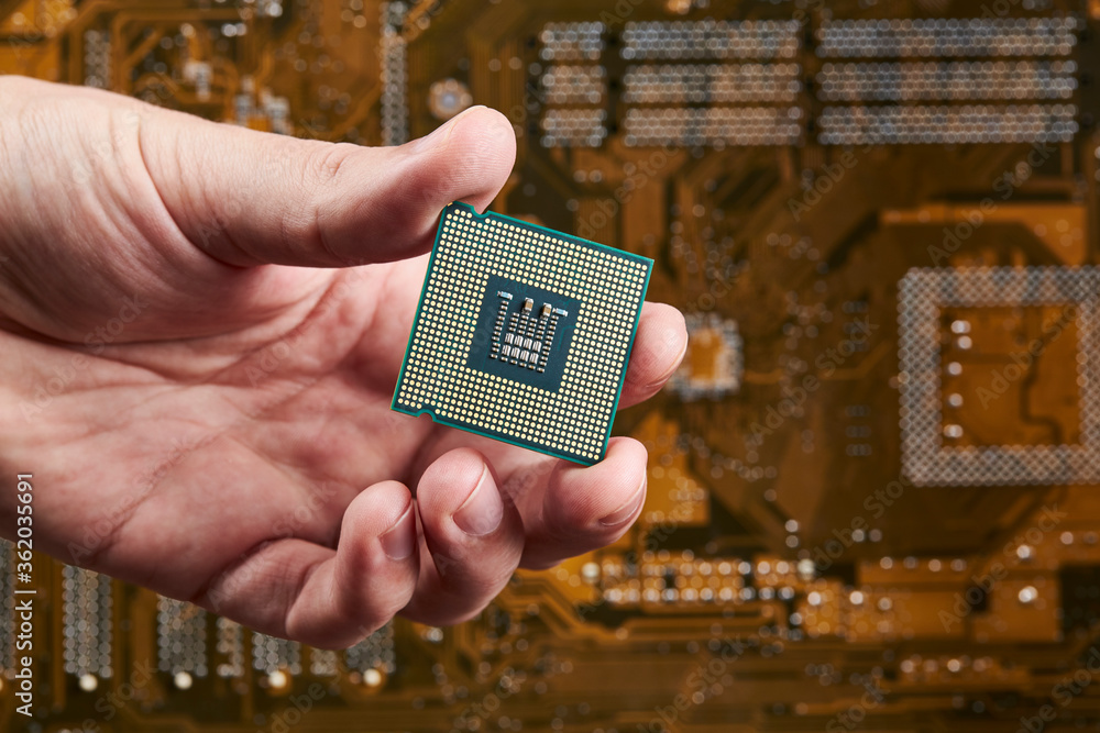 Aufkleber technician person holds cpu central processor unit over circuit board background. hardware research 