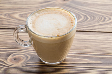 Hot Coffee in Transparent Cup with Froth on Wooden background