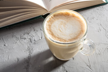 transparent cup of coffee with Latte art on concrete table with book