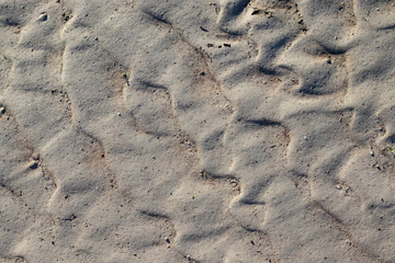 Traces left in the gray sand in the form of waves. View from above.