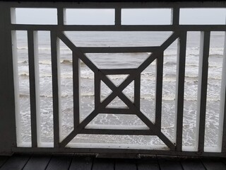 Seawall view from deck overlooking Gulf of Mexico. Geometric shaped railing along boardwalk. Repeating square pattern with ocean in the background.