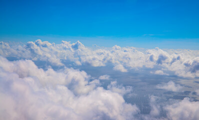 Blue sky with fluffy clouds, natural cloudscape view from plane window. Airplane travel concept. White clouds overcast