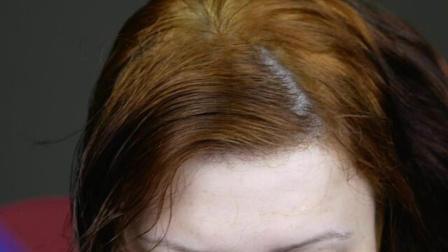 Woman combing her red damaged hair.Brightens dark strands.Self-coloring at home.