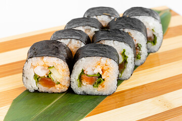 Maki Sushi Rolls set on wooden bamboo board. Japanese traditional Cuisine. White background.