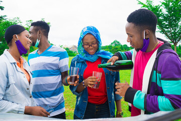 young black people standing in a park and pouring drinks into their glass cups