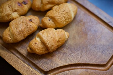 Close up view of homemade croissants. A few pieces of croissants on the serving board. Blurry background.